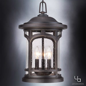 The UQL1109 Rustic Outdoor Pendant Light from the Sydney Collection by Urban Ambiance features a Parisian Bronze finish and marine-grade construction. Measuring 18 inches high by 11 inches wide, this outdoor pendant showcases seeded glass panels and three candle-style bulbs inside. The fixture stands out against the neutral gray background, with the Urban Ambiance logo displayed in the lower right corner.