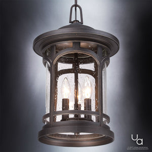 The Urban Ambiance UQL1109 Rustic Outdoor Pendant Light from the Sydney Collection, measuring 18 inches high by 11 inches wide in a Parisian Bronze finish, features clear seeded glass panes and three candle-style bulbs. Its marine-grade construction is showcased as it hangs elegantly against a gradient gray background.