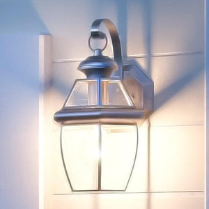 A unique Urban Ambiance UQL1141 Colonial Outdoor Wall Light, 11.5"H x 7"W, with an Aged Silver Finish from the Cambridge Collection on a wall next to a