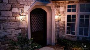 A beautiful stone house with a doorway lit up at night, featuring the UQL1145 Colonial Outdoor Wall Light from the Cambridge Collection.