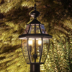 A unique lamp, the Urban Ambiance UQL1148 Colonial Outdoor Post Light, 21"H x 11"W, Black Silk Finish from the Cambridge Collection, stands gorgeously in front of a
