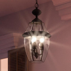 A unique Colonial Outdoor Pendant Light from the Cambridge Collection with a Black Silk Finish is hanging in a room with a pink wall.