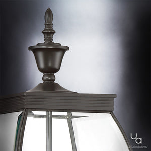 Close-up of the top portion of the Urban Ambiance UQL1174 Colonial Outdoor Post Light from the Manchester Collection, featuring a vintage-transitional style in a medieval bronze finish with clear glass panels, set against a neutral gradient background.