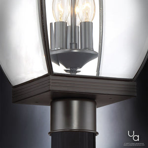Close-up of the UQL1174 Colonial Outdoor Post Light from Urban Ambiance’s Manchester Collection, featuring a vintage-transitional design with clear glass panels, visible bulbs, and a medieval bronze finish on its dark metal frame. Urban Ambiance logo appears in the bottom right corner.
