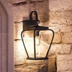 A gorgeous French Country Outdoor Wall Lamp by Urban Ambiance on a stone wall.
