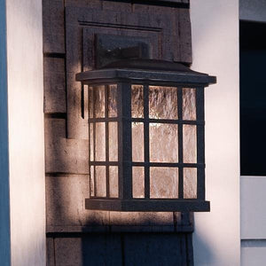 A gorgeous Craftsman Outdoor Wall Light from the Zurich collection, featuring a unique Parisian Bronze finish, on the side of a house.