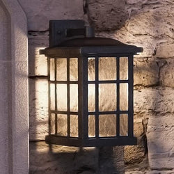 A UQL1236 Craftsman Outdoor Wall Light, 17"H x 11"W, Black Silk Finish from the Zurich Collection by Urban Ambiance on a stone wall adds a touch of luxury.