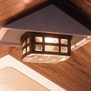 A beautiful UQL1249 Craftsman Outdoor Ceiling Light, 5.75"H x 12"W, Parisian Bronze Finish, Zurich Collection lighting fixture hanging on a wooden ceiling by Urban