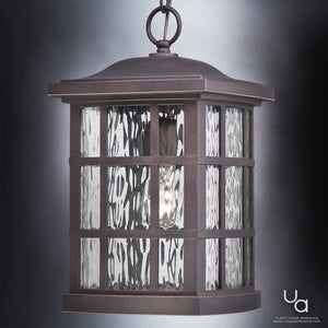 The Urban Ambiance UQL1251 Craftsman Outdoor Pendant Light from the Zurich Collection features a Parisian Bronze finish, clear textured water glass diffuser panels, a metal grid design, and marine-grade construction. Measuring 15″ high by 9.5″ wide, this elegant outdoor pendant light beautifully showcases a visible bulb against any exterior setting.