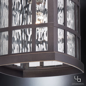 Close-up of the Urban Ambiance UQL1251 Craftsman Outdoor Pendant Light from the Zurich Collection, featuring a marine-grade Parisian Bronze finish and textured water glass panels, illuminated against a plain background.