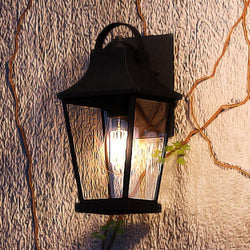 A luxury Tudor Outdoor Wall Light, 12.5"H x 6"W, Black Sand Finish from the Constanta Collection on a stone wall.