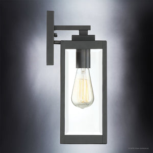The Urban Ambiance UQL1330 Farmhouse Outdoor Wall Light from the Quincy Collection features a rectangular black steel frame with a clear glass enclosure, showcasing an exposed vintage-style bulb against a gradient gray background. Measuring 14.25″ high by 5″ wide, this modern wall sconce beautifully blends timeless farmhouse charm with contemporary elegance.