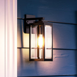 An UQL1330 Farmhouse Outdoor Wall Light, 14.25"H x 5"W, Black Finish, Quincy Collection by Urban Ambiance on a blue wall.