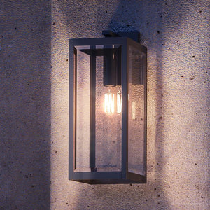 A gorgeous farmhouse outdoor wall lamp from the Quincy Collection, with a black finish, mounted on a concrete wall.