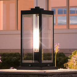 A gorgeous outdoor pier light from the Quincy Collection by Urban Ambiance, featuring a unique Modern Farmhouse design in a Natural Black Finish, displayed on a table in front of a building.
