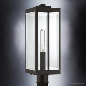 Featuring a visible tube-shaped bulb encased in clear beveled glass panels, the Urban Ambiance UQL1353 Modern Farmhouse Outdoor Post/Pier Light from the Quincy Collection is mounted on a black pole against a neutral background; its estate bronze finish and 20.5″ height by 7″ width make it an ideal choice for modern farmhouse outdoor lighting.