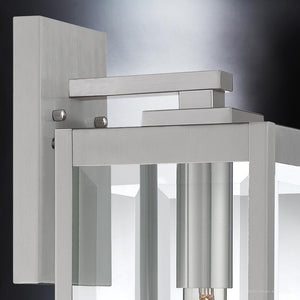 Close-up of the Urban Ambiance UQL1361 Modern Farmhouse Outdoor Wall Light from the Quincy Collection, showcasing its rectangular metal frame, glass panels, and cylindrical bulb holder. Measuring 17″ high by 6″ wide with a sleek stainless steel finish, this stylish fixture combines classic charm with contemporary design—making it an ideal addition to any exterior space.
