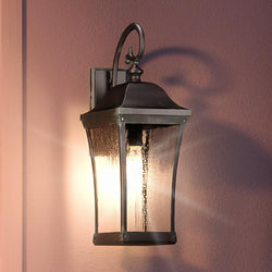 A unique Urban Ambiance UQL1422 Antique Outdoor Wall Light with an Olde Patina Finish, illuminating a pink wall.
