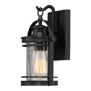 The Urban Ambiance UQL1430 Nautical Outdoor Wall Light from the Cannes Collection features a Black Silk finish, clear seeded glass shade, and vintage-inspired lantern bulb. Measuring 11.5″ high by 6.75″ wide, this rectangular wall-mounted sconce is photographed illuminated against a white background—an elegant seedy glass outdoor fixture perfect for enhancing your exterior décor.
