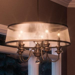 The Urban Ambiance UQL2180 Mediterranean Chandelier from the Guadalajara Collection features a Parisian Bronze finish and measures 15.5"H x 25"W, adding elegant indoor lighting near large windows.