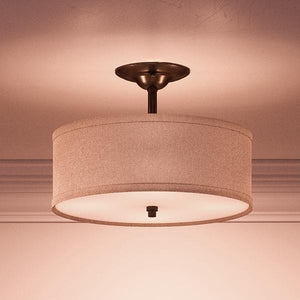 The Urban Ambiance UQL2231 Modern Farmhouse Semi-Flush Ceiling Light from the Dublin Collection features a khaki fabric drum shade and a bronze-finished metal base, measuring 12 inches high by 17 inches wide, and provides soft, warm illumination to any room.