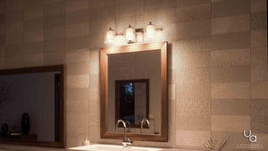 A bathroom vanity with a wooden-framed mirror, a white sink, and metallic faucet is set against textured beige tile walls, illuminated above by the Urban Ambiance UQL2402 Modern Bathroom Vanity Light from the Napa Collection, featuring a three-light fixture in polished chrome finish (6″ H x 21″ W).