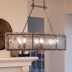 A beautiful UQL2870 Industrial Chandelier, 23.5"H x 39"W, Silver Etch Finish, from the Nantes Collection by Urban Ambiance hanging over a fireplace