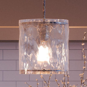 A unique lighting fixture, the Urban Ambiance UQL2871 Industrial Pendant from the luxury Nantes Collection, hangs elegantly from a tiled wall.