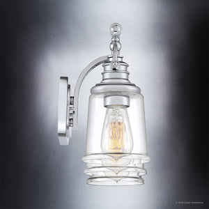 The Salford Collection UQL2881 Industrial Bathroom Vanity Light by Urban Ambiance features a polished chrome finish and clear glass, combining modern sophistication with industrial bath lighting. Shown here wall-mounted with a visible filament bulb against a gradient gray background, this 9.5″ high by 23″ wide fixture elevates any bathroom décor.