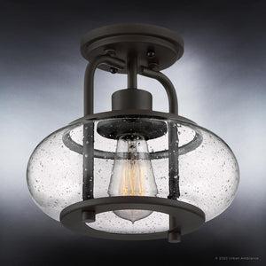 From the Urban Ambiance Clearwater Collection, the UQL3271 Utilitarian Ceiling Light features an oversized clear seedy glass shade showcasing a vintage-inspired bulb inside. It has a dark bronze metal frame and a round base for ceiling attachment. Size: 9.28