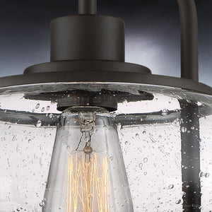Close-up of the UQL3271 Utilitarian Ceiling Light by Urban Ambiance in the Clearwater Collection, showcasing a raindrop-textured glass shade and vintage-inspired bulbs mounted on a dark bronze frame.