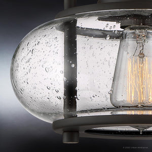 Close-up of a glass light fixture from Urban Ambiance's Clearwater Collection, showcasing a water droplet texture and an exposed vintage bulb inside the UQL3271 Utilitarian Ceiling Light, with dimensions of 9.28