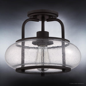 From Urban Ambiance's Clearwater Collection, the UQL3281 Utilitarian Ceiling Light features a vintage bulb inside an oversized clear seedy glass shade, elegantly mounted on a dark bronze-finish background.