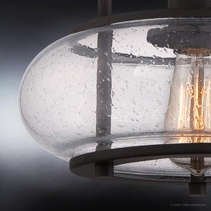 A close-up view shows the UQL3281 Utilitarian Ceiling Light by Urban Ambiance, featuring oversized clear seedy glass shades with a vintage-inspired bulb that shimmers like water droplets against a gradient gray and blue backdrop.