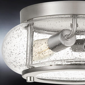 Showcasing the Urban Ambiance UQL3290 Utilitarian Ceiling Light from the Clearwater Collection, this fixture features a brushed nickel finish and a clear, bubbled seeded glass shade that reveals an Edison-style bulb for a modern farmhouse ceiling light aesthetic. Measures 5.75″H x 12″W.