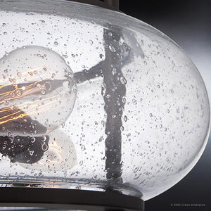 Close-up of a round lampshade from the Urban Ambiance UQL3311 Utilitarian Ceiling Light, featuring a vintage-style bulb. The clear seedy glass surface has small bubble textures, adding elegance and echoing the charm of the Clearwater Collection.