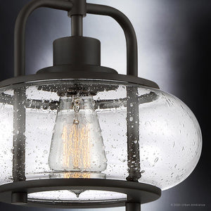 Close-up of the UQL3331 Utilitarian Pendant Light by Urban Ambiance from the Clearwater Collection, with a raindrop-textured glass shade and visible filament bulb, nodding to nautical aesthetics, against a gradient background. Dimensions: 9.5