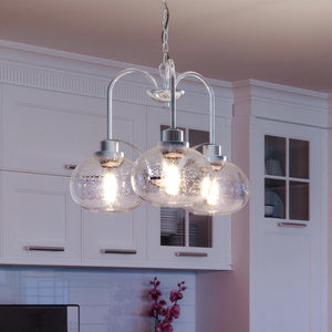 A kitchen with three beautiful Utilitarian Chandeliers by Urban Ambiance hanging above the counter.