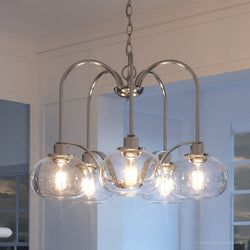 A Unique Utilitarian Chandelier, 19"H x 26.1"W, Brushed Nickel Finish, Clearwater Collection light fixture in a kitchen with a glass shade.