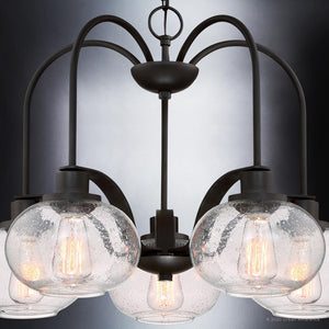 Urban Ambiance's UQL3361 Utilitarian Chandelier from the Clearwater Collection features six curved arms with globe-shaped seedy glass shades in a dark bronze finish. Vintage-inspired bulbs create a striking contrast against a gray gradient backdrop, measuring 19