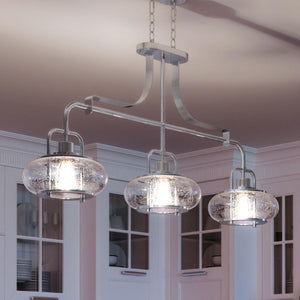 Three beautiful UQL3380 Utilitarian Chandeliers, 21.55"H x 38"W, Brushed Nickel Finish, Clearwater Collection hanging over a kitchen island from the brand Urban Amb