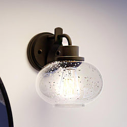 An Urban Ambiance wall light with a luxurious UQL3392 Utilitarian Wall Light, 9.5"H x 8"W, Black Bronze Finish, Clearwater Collection glass globe on it.