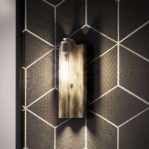A black and white tiled wall with a unique wooden wall sconce.