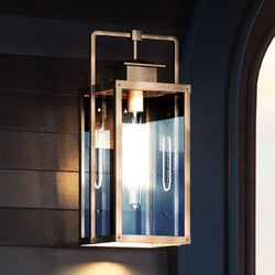 A beautiful UEX1037 Lux Industrial Outdoor Wall Sconce with a luxury antique brass finish and a blue glass shade hanging on a wall.