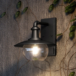 An Urban Ambiance UEX1090 Farmhouse Outdoor Wall Sconce 11''H x 11''W lighting fixture with a unique Matte Black Finish from the Easton Collection on a stone