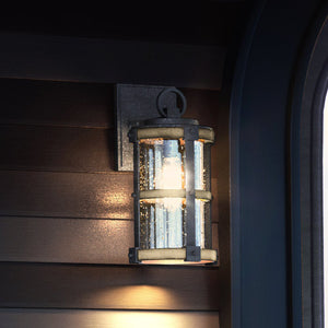 A beautiful UEX1100 Farmhouse Outdoor Wall Sconce in an Olde Iron Finish, from the gorgeous Jackson Collection by Urban Ambiance, on a wall next to a window.