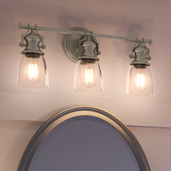 A bathroom with three beautiful UEX2455 New Traditional lighting fixtures above a mirror.