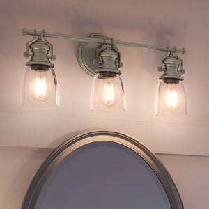 A bathroom with three beautiful UEX2455 New Traditional lighting fixtures above a mirror.