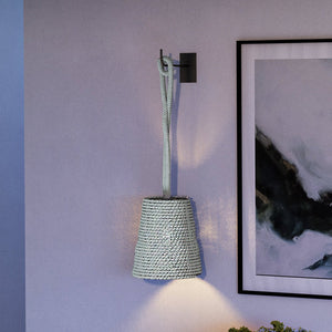 A luxurious lamp hanging on a wall next to a plant.