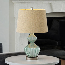A gorgeous UEX7090 Shabby-Chic Table Lamp with a beige shade, providing luxury lighting fixture in front of a fireplace.